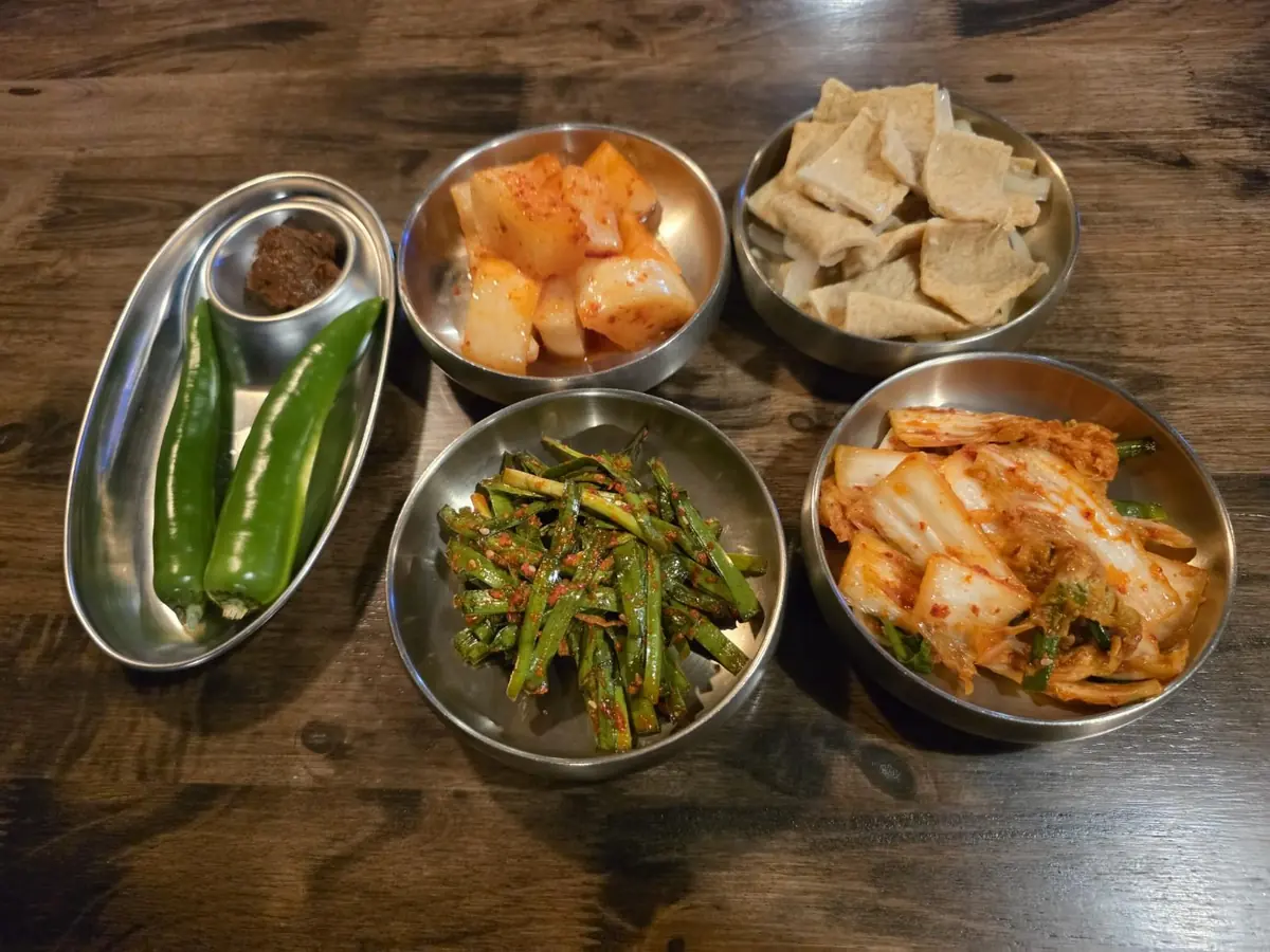 A table of banchan: kimchi, kkakdugi, chive salad and more — WuRim Korean Slow Food (우림), Bangkok